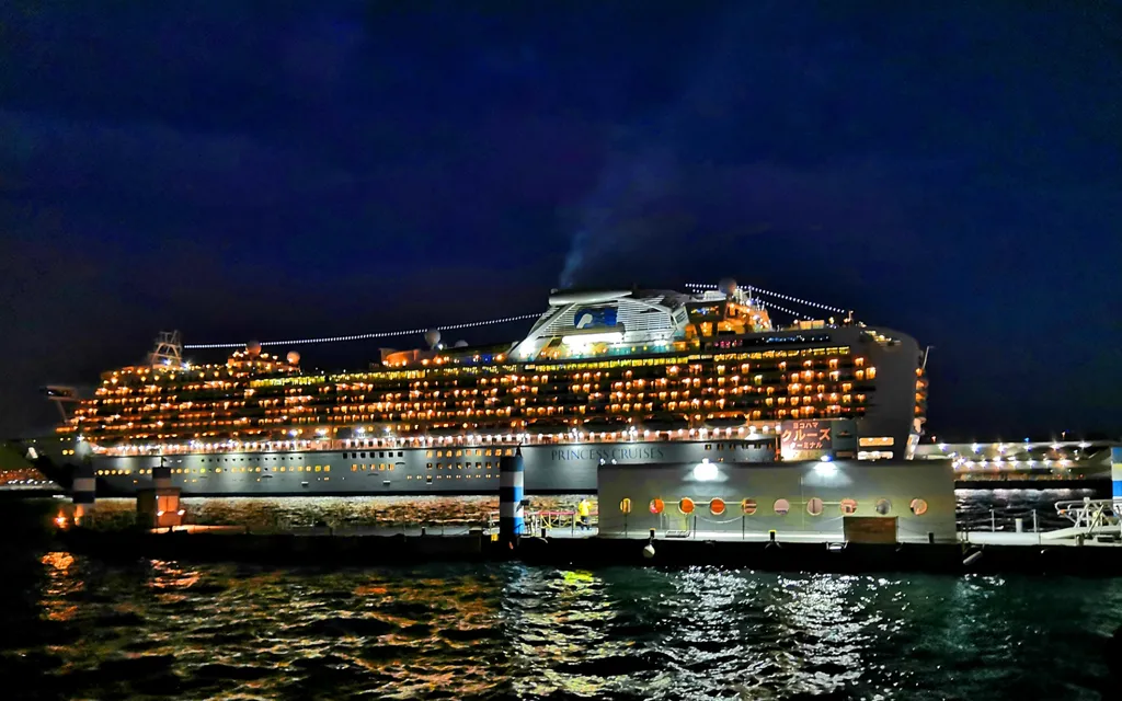 港に停泊する豪華客船。客室の明かりがキラキラ輝く